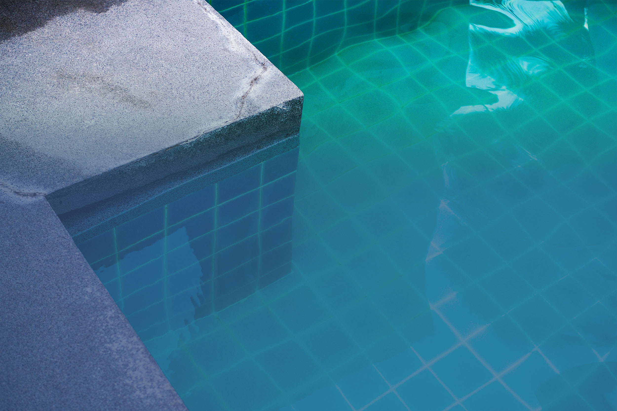 Piscine surélevée en pierre naturelle avec terrasse carrelée grand format – Réalisation Émotion Piscine en Wallonie